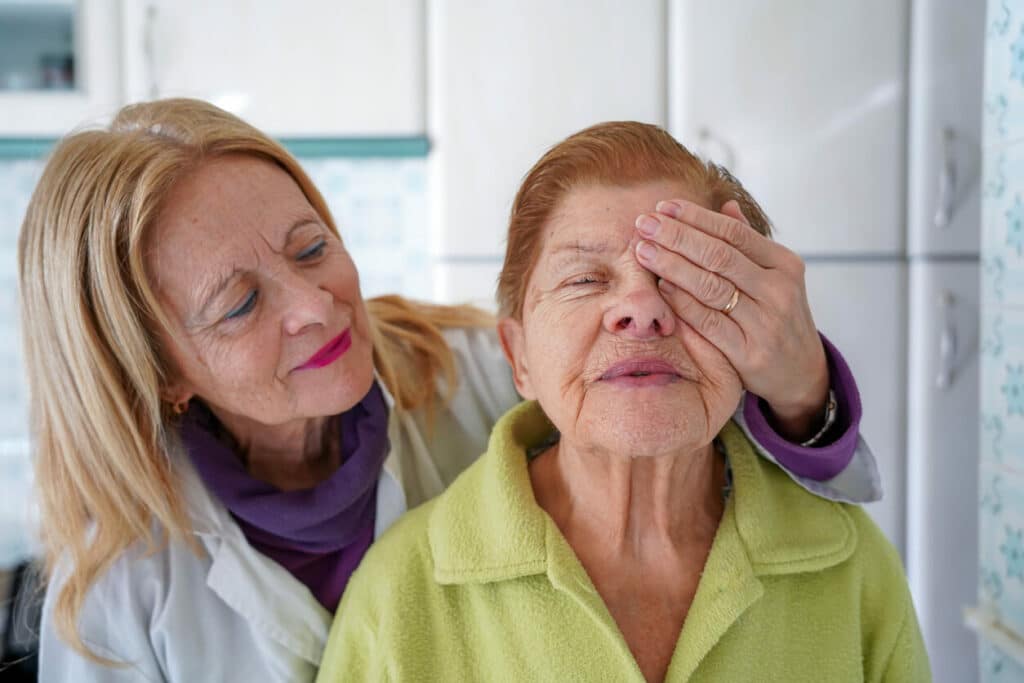 A senior female ophthalmologist is covering an elderly woman's eye during a diabetic eye exam.