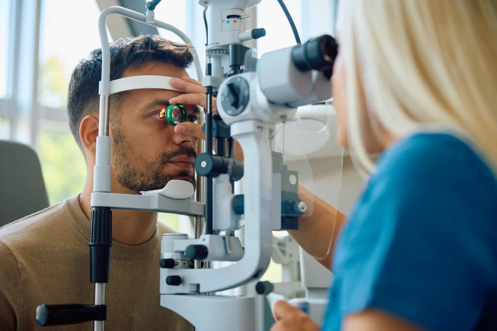 A young man is having his eyesight tested at an ophthalmologist's office by an eye doctor.