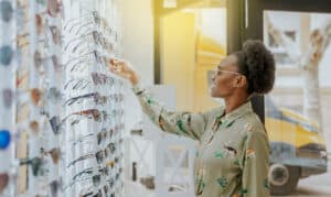 A young African-American girl is shopping for glasses at an optical boutique.