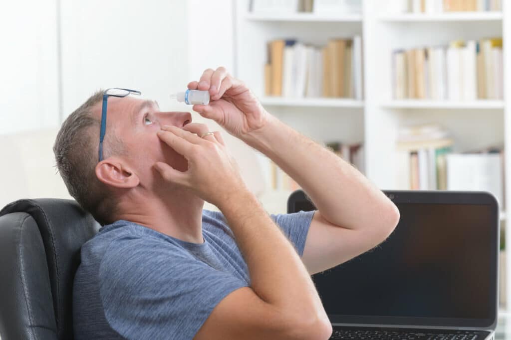 A man applying eye drops for dry eye treatment.