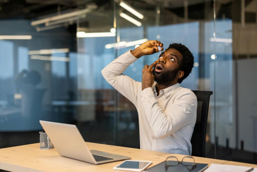 A man drips medicine drops into his dry eyes.