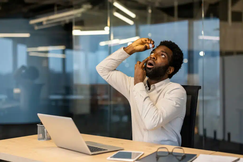 A man drips medicine drops into his dry eyes.