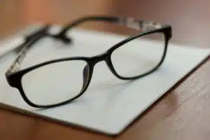Notebook, pen and prescription glasses on the table.